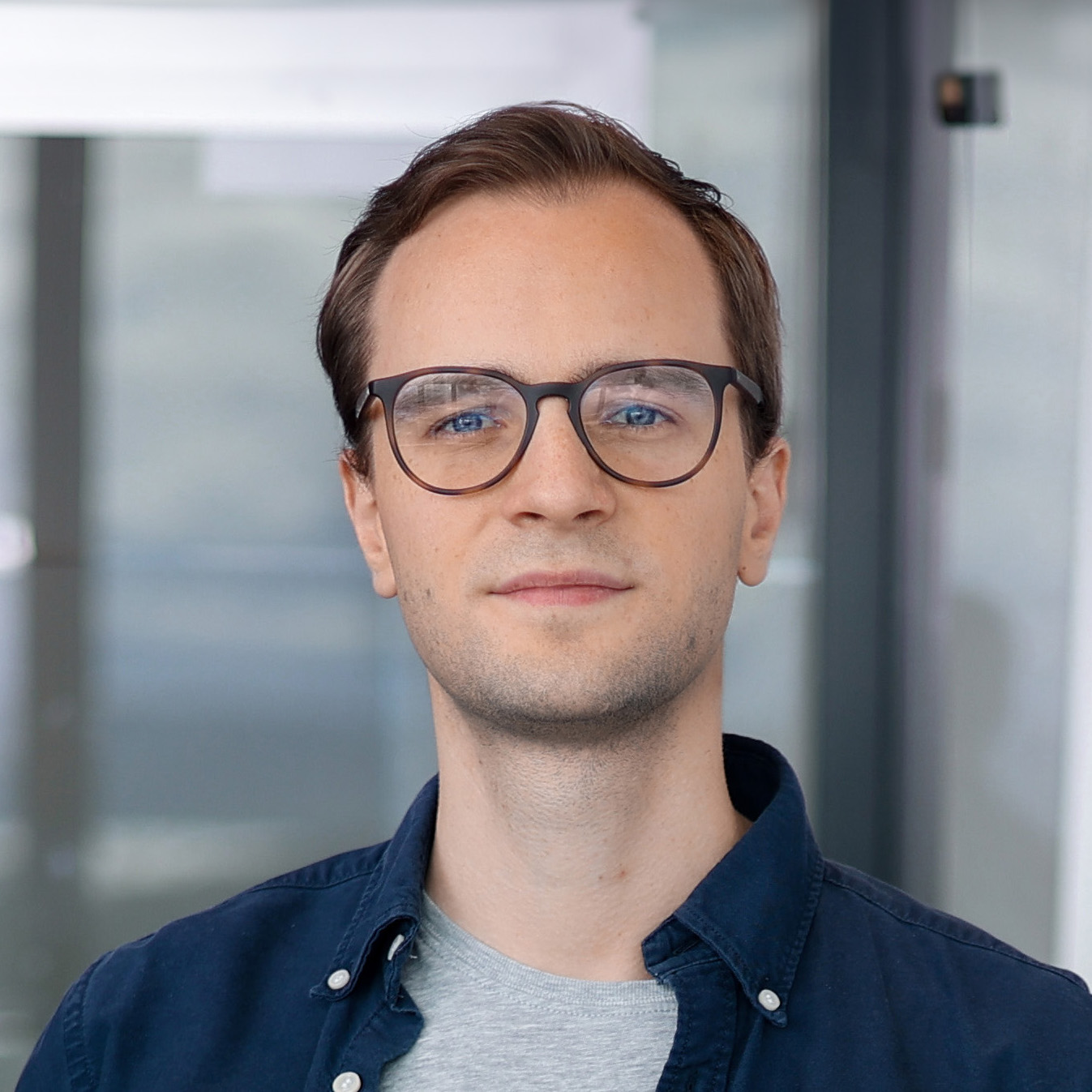 Picture of Daniel smiling to the camera with a slightly orange blurred background
