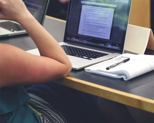 A student sitting on her laptop in a lecture